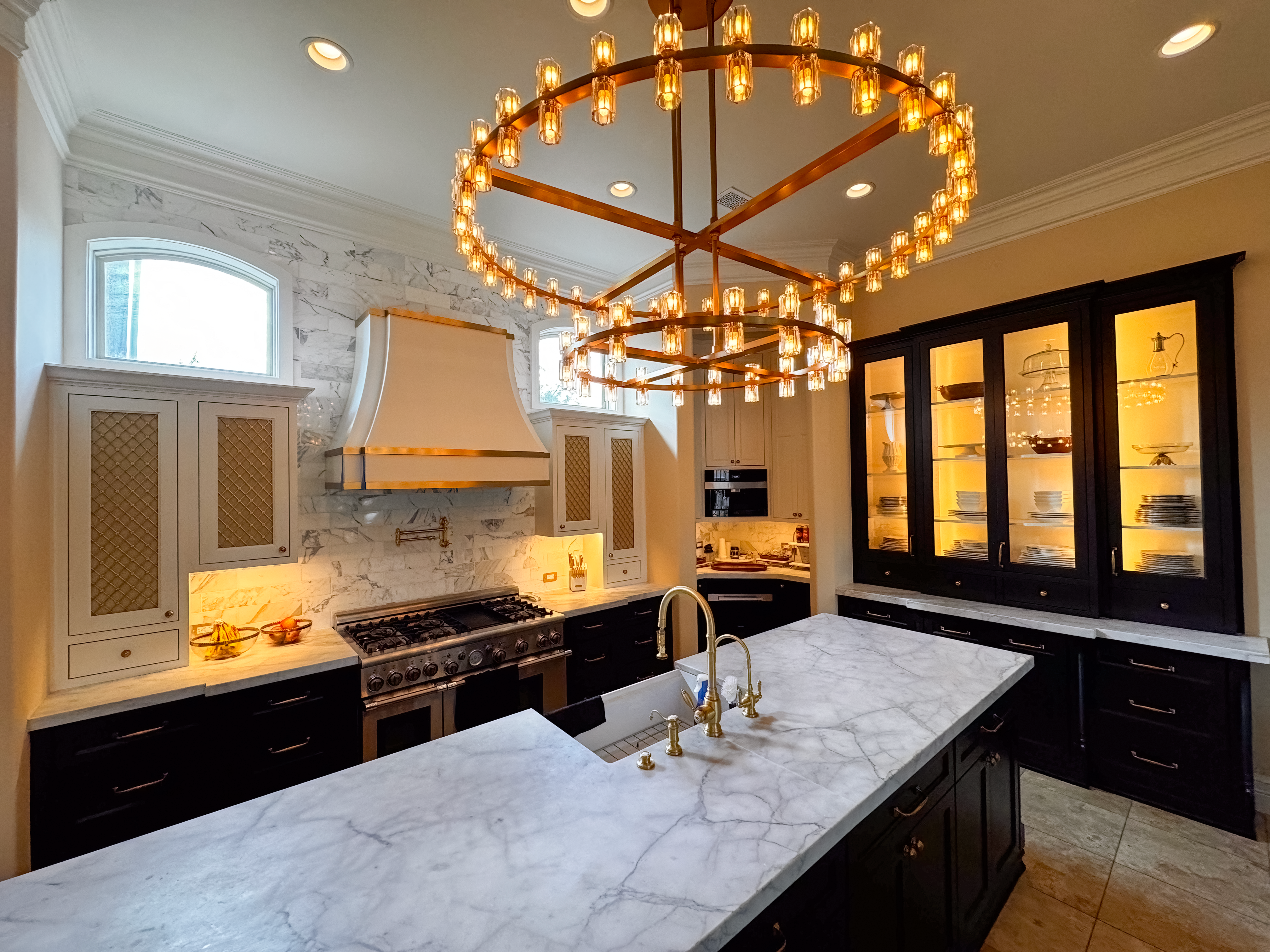 Twin marble islands beneath a double tiered brass chandelier