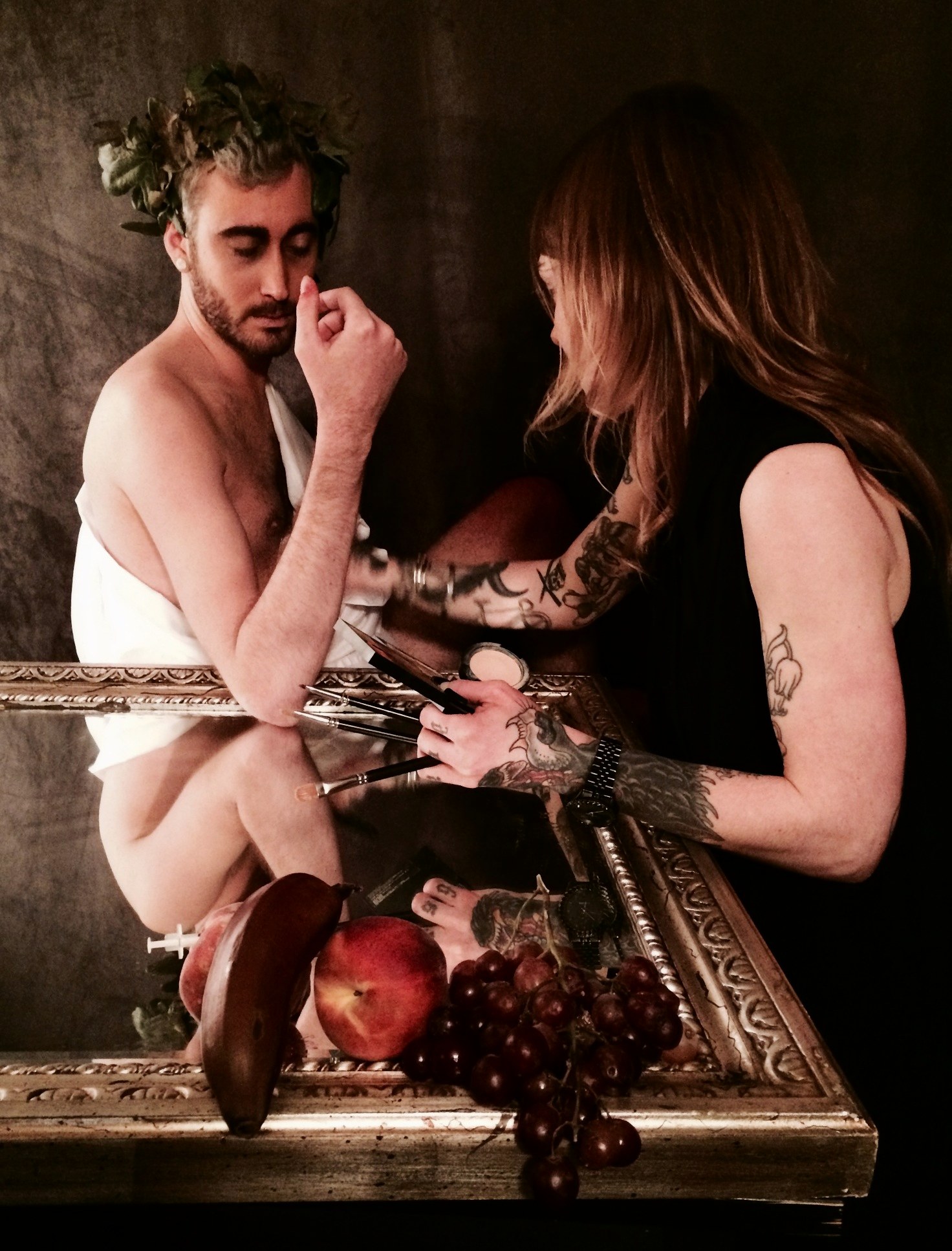 The model being made up on set, seated behind the gilt frame and the fruit, in Caravaggio’s pose.