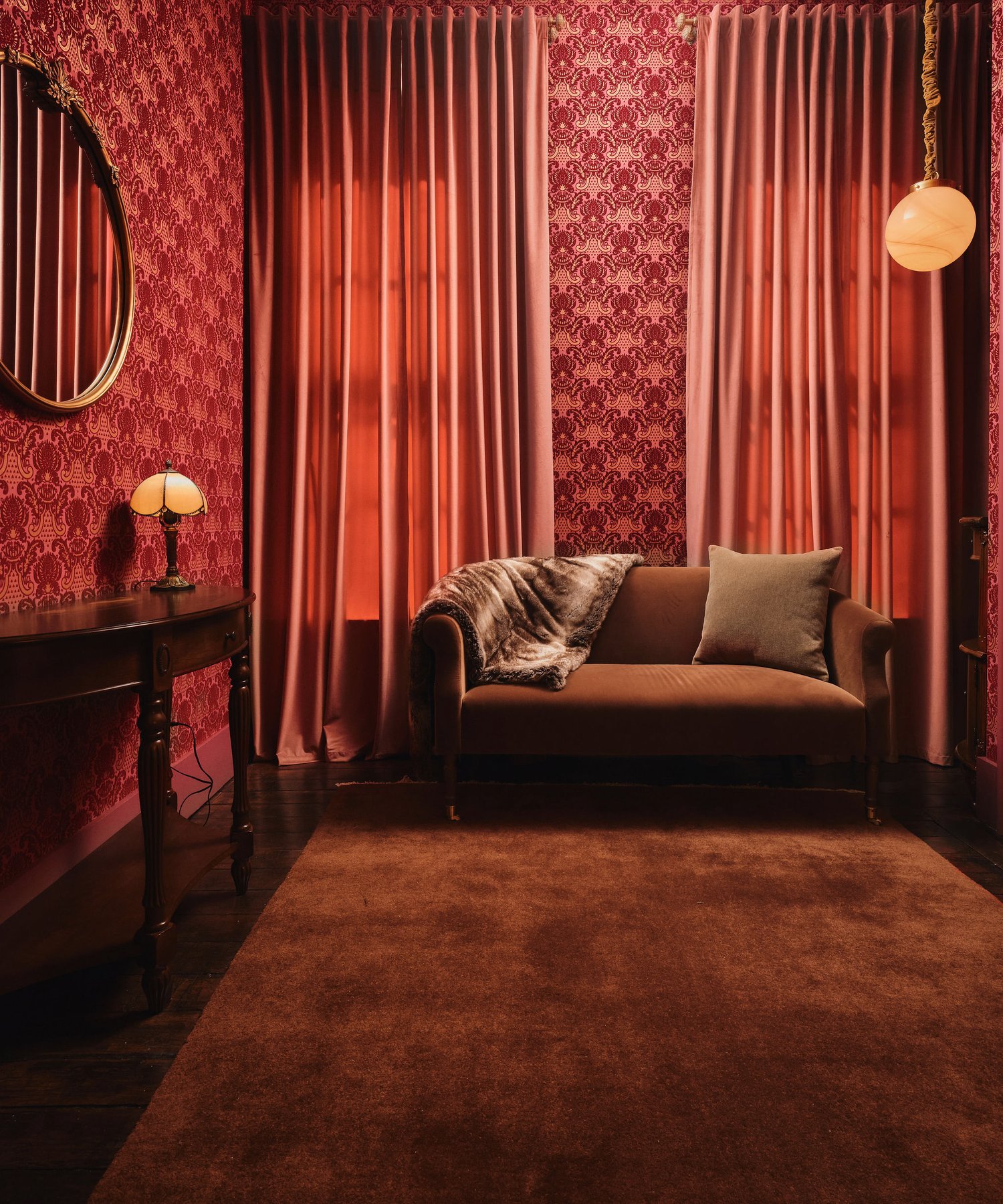 Velvet sofa beneath silk curtains in the dressing room, an alabaster globe overhead and damask climbing the walls